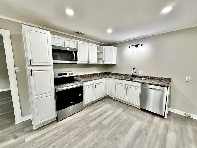 a white kitchen with granite countertop stainless steel appliances