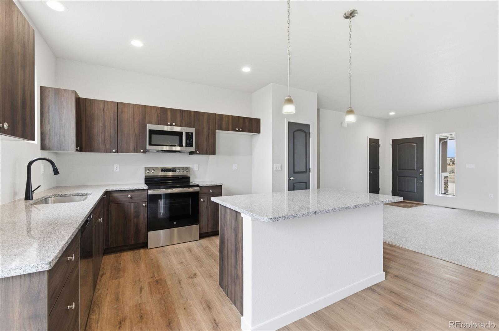 24615 Big Springs Road Pueblo West, CO 81007 - Photo 7 of 24 a kitchen with stainless steel appliances granite countertop a sink refrigerator and microwave