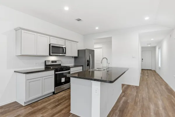 a kitchen with granite countertop a sink stove and refrigerator