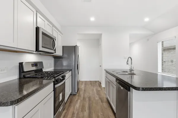 a kitchen with granite countertop a sink stove and refrigerator