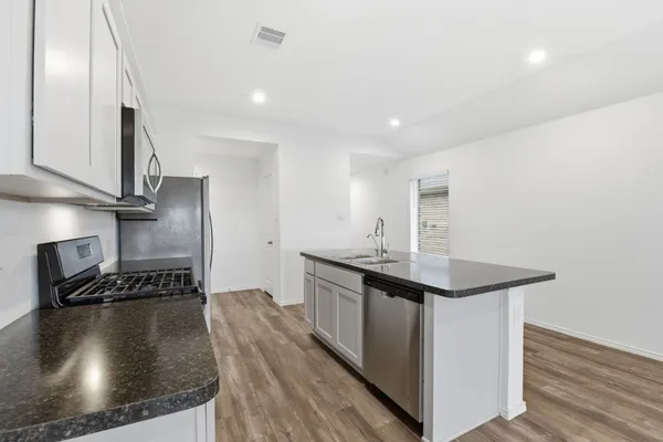 a kitchen with kitchen island a sink stove and wooden floor