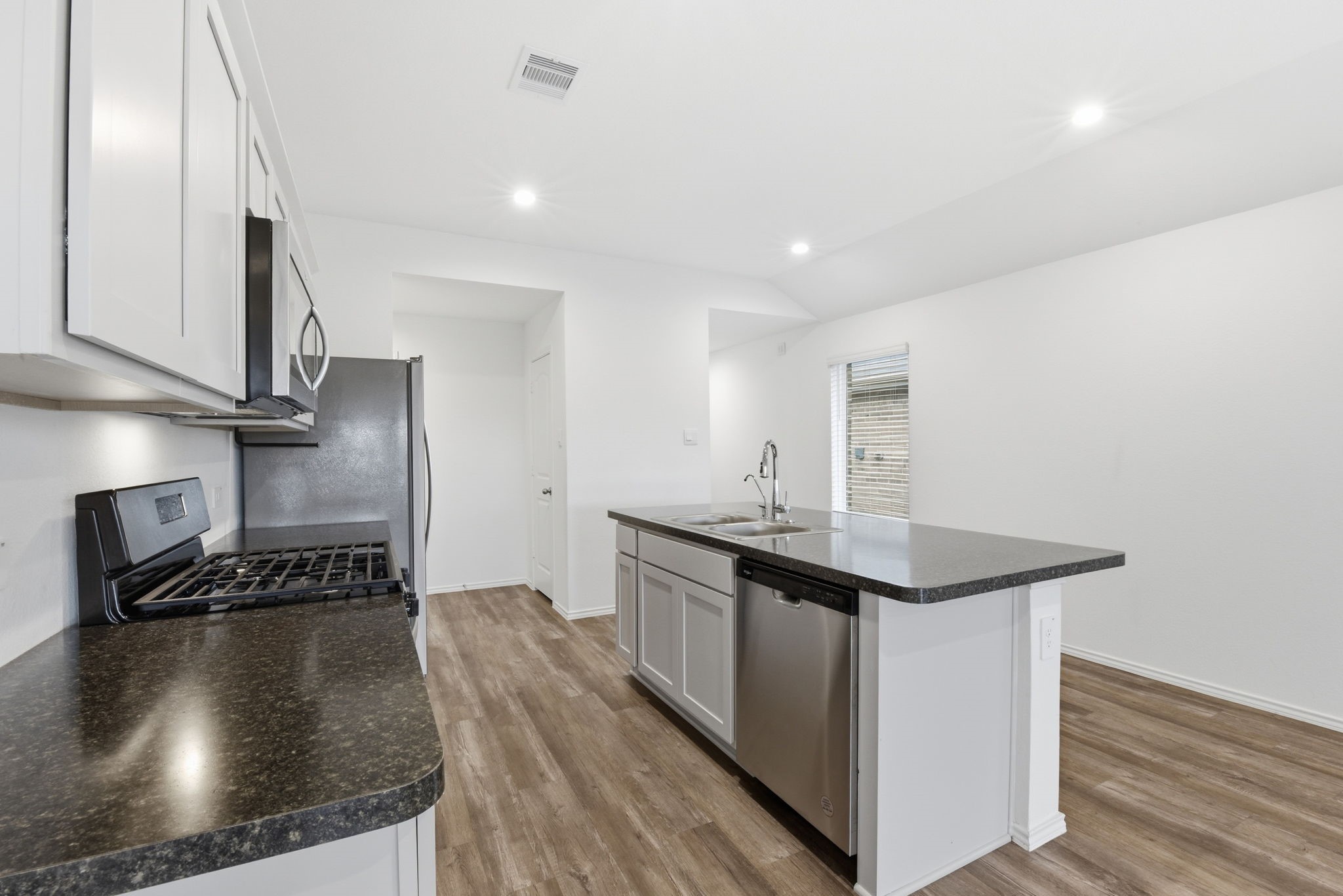 24343 Saddlestone Green Drive Spring, TX 77373 - Photo 21 of 43 a kitchen with kitchen island a sink stove and wooden floor