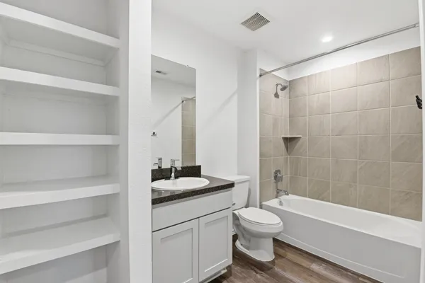 a bathroom with a bath tub sink mirror vanity and toilet
