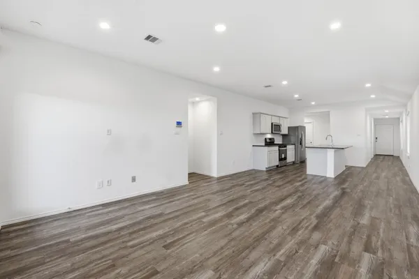 a view of kitchen with kitchen island a sink wooden floor and a refrigerator