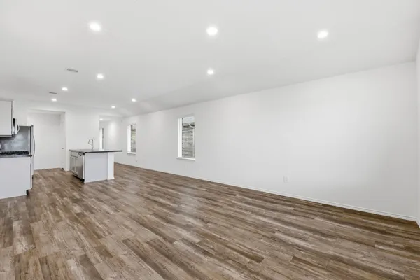 a view of kitchen and empty room with wooden floor