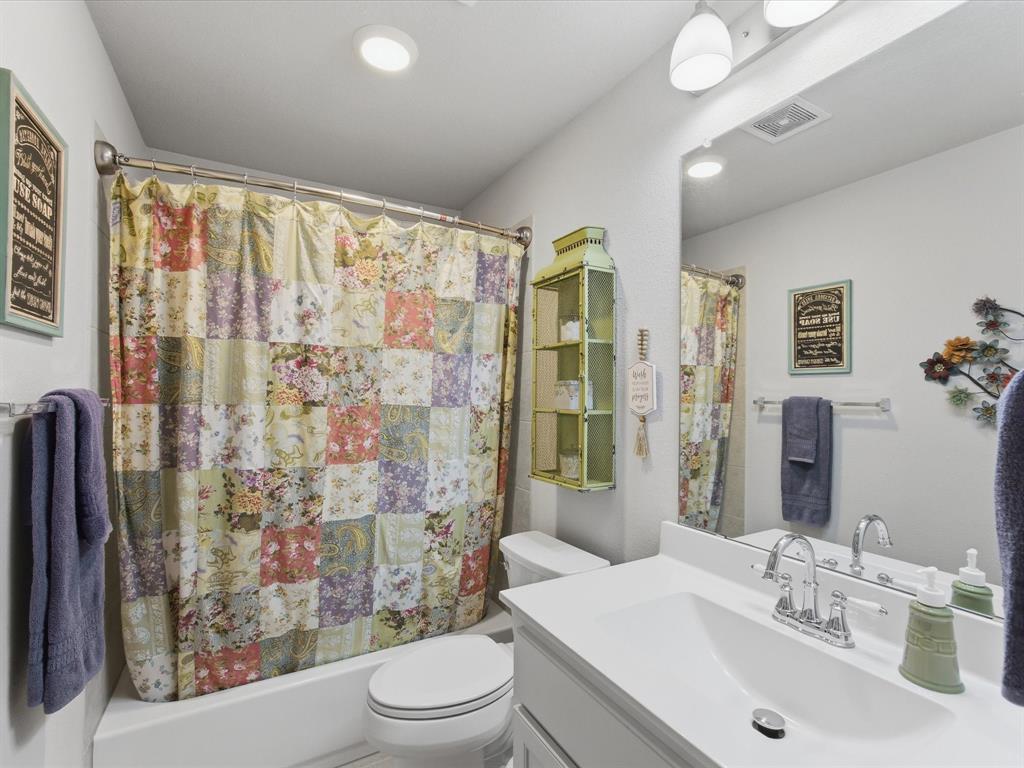 129 Springwood Ranch Loop Springtown, TX 76082 - Photo 23 of 26 Bathroom featuring a white vanity with an integrated sink and chrome hardware, a full-width mirror, and a white tub with a shower