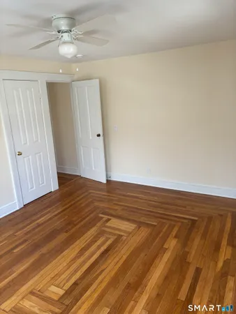 an empty room with wooden floor chandelier fan and windows