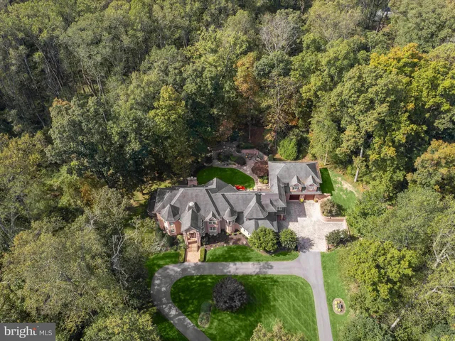 an aerial view of residential house with outdoor space and trees all around