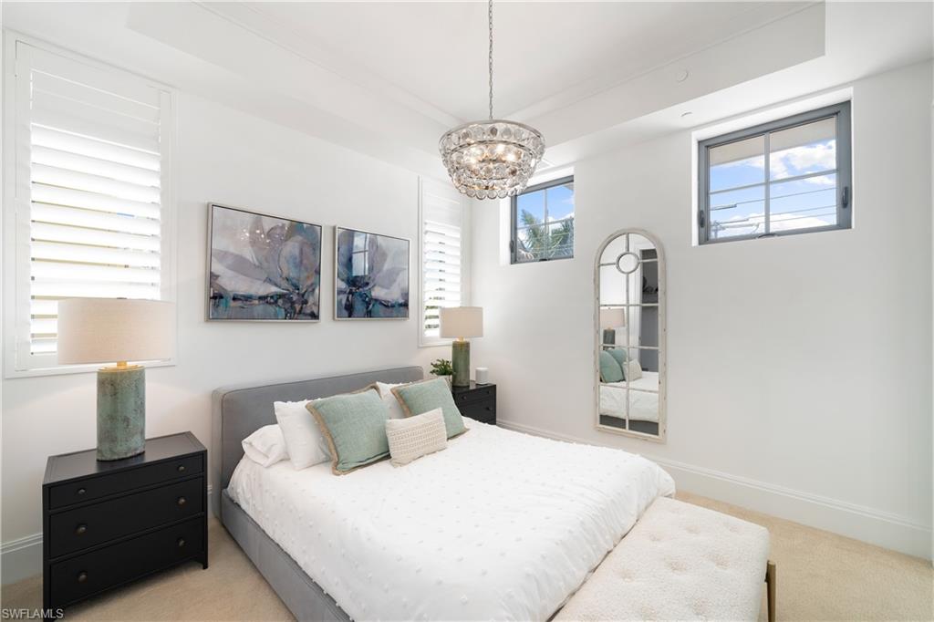 875 6th Avenue South, Unit 304 Naples, FL 34102 - Photo 18 of 40 a bedroom with a bed and a chandelier
