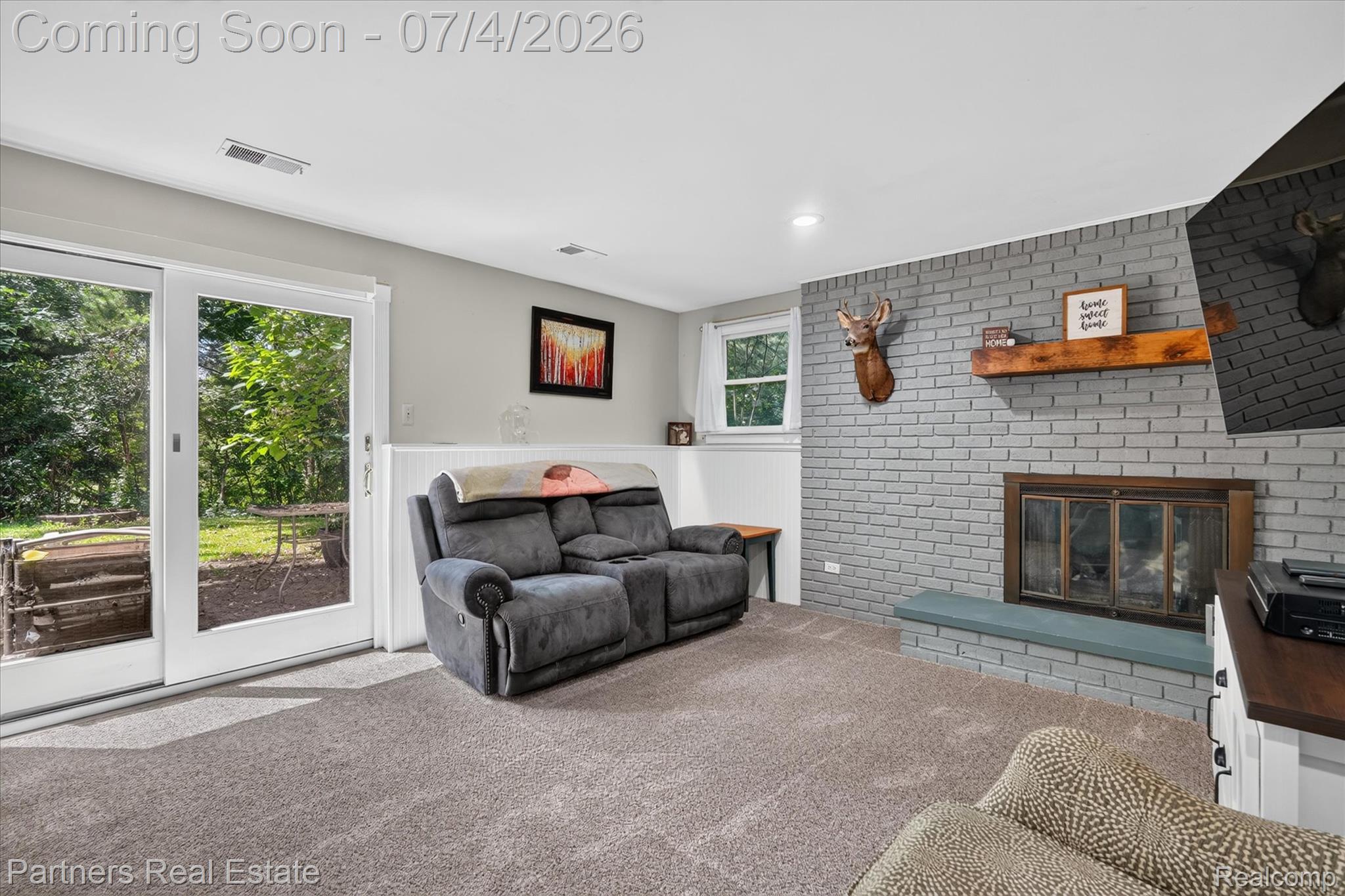 2500 Hubert Road Brighton, MI 48114 - Photo 19 of 53 Spacious room featuring a painted brick fireplace with a wood-finish mantel and hearth
