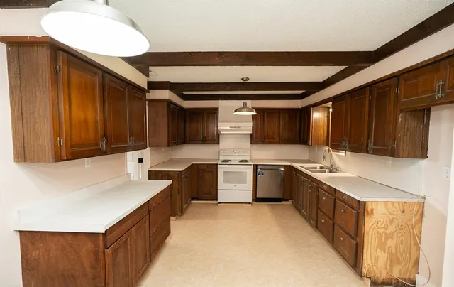 a large kitchen with a large counter top space a sink stainless steel appliances and cabinets