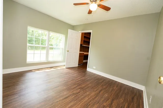 a view of a hallway with wooden floor and cabinets