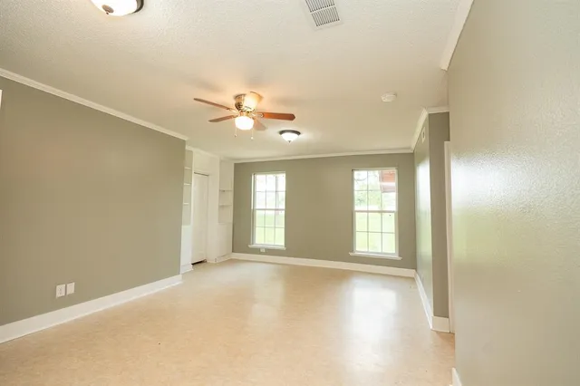 an empty room with windows and fan
