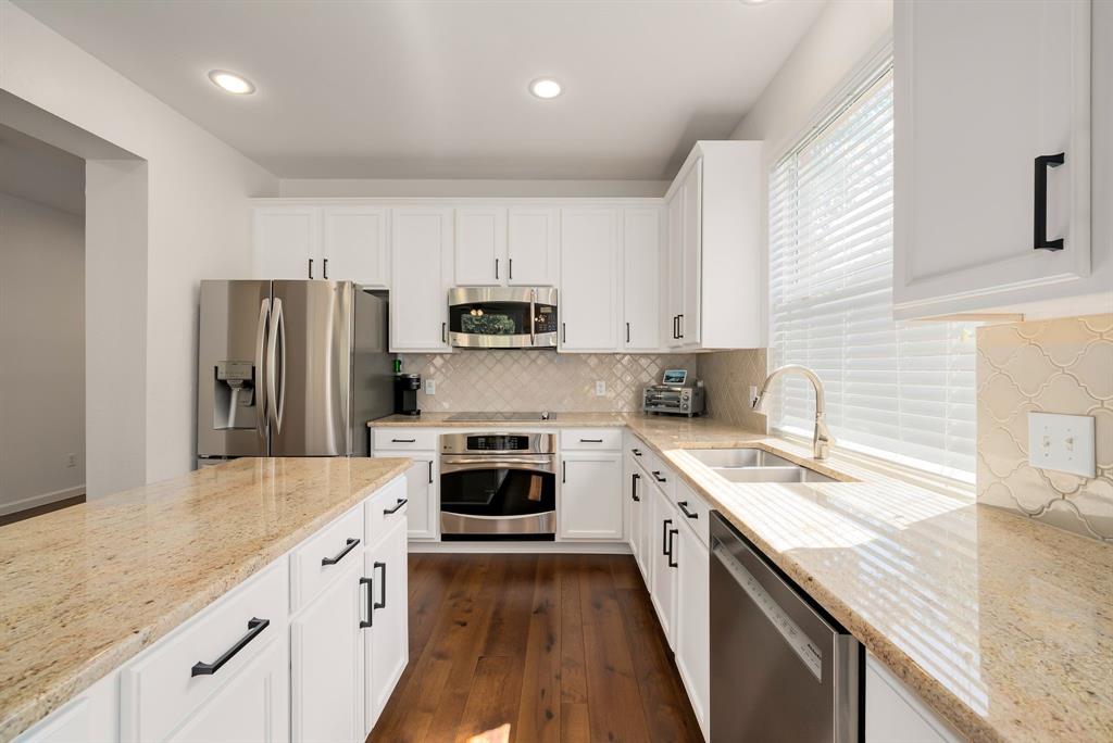 2524 Windgate Drive Frisco, TX 75033 - Photo 4 of 38 a kitchen with kitchen island granite countertop a sink stainless steel appliances and cabinets