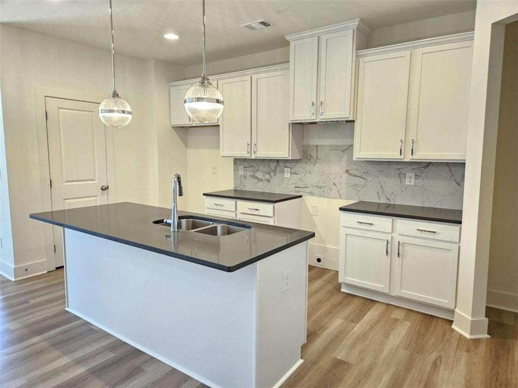 a kitchen with kitchen island granite countertop a sink appliances cabinets and wooden floor