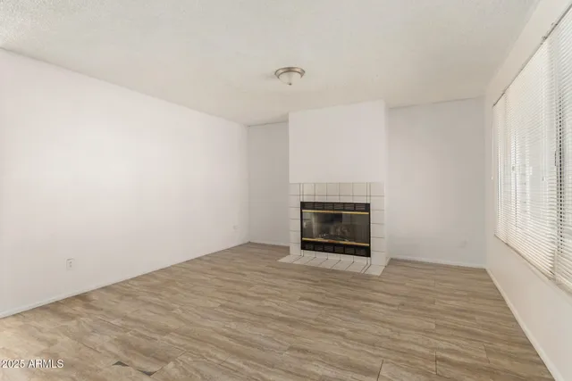 a view of empty room with wooden floor and fireplace