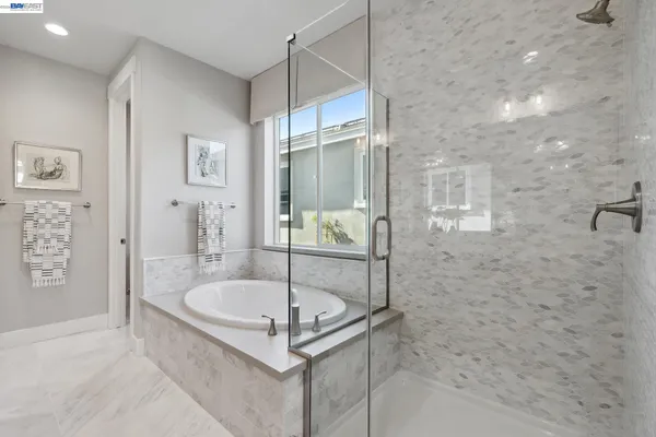 a bathroom with a tub a mirror and shower