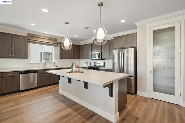 a large kitchen with stainless steel appliances granite countertop a sink a oven a refrigerator and a large window with wooden floor
