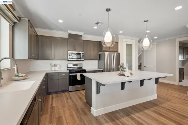 a kitchen with a sink a counter top space stainless steel appliances and cabinets