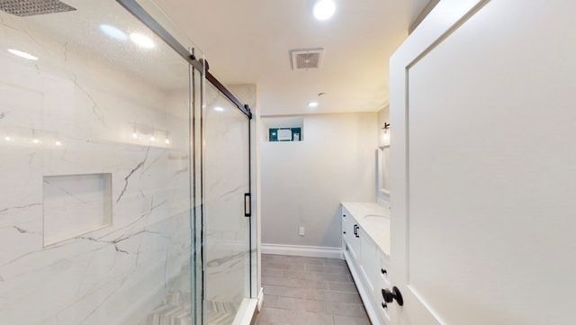 a bathroom with a glass door shower door and a sink