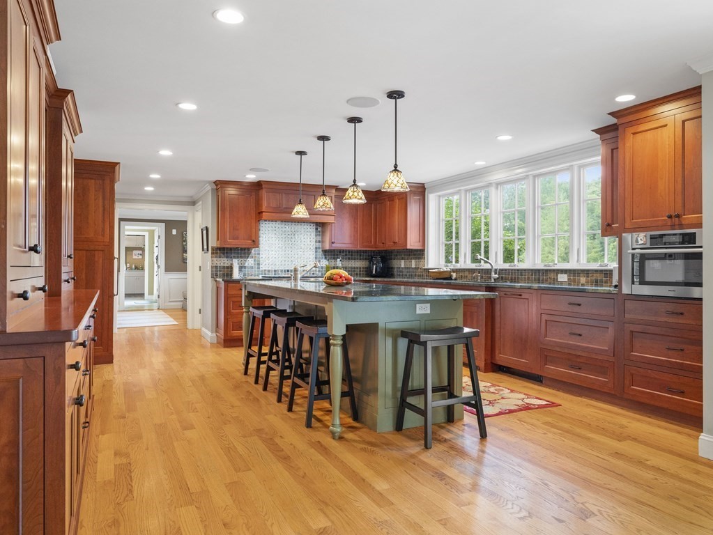 20 Jackson Road Sherborn, MA 01770 - Photo 7 of 29 a open kitchen with stainless steel appliances granite countertop a stove top oven a refrigerator a sink and a dining table with wooden floor