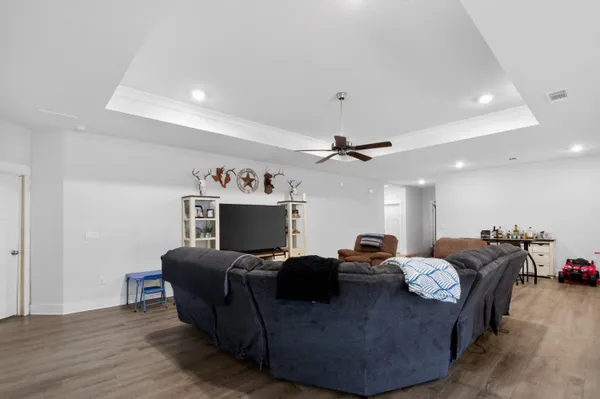 a living room with furniture a ceiling fan and a wooden floor
