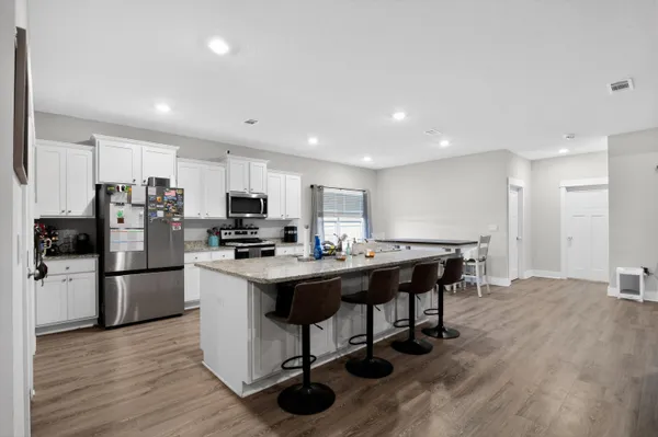 a living room with stainless steel appliances kitchen island granite countertop furniture wooden floor and a view of kitchen