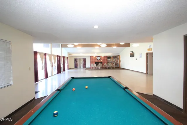 a room with stainless steel appliances kitchen island granite countertop a refrigerator a sink dishwasher and a stove with wooden floor