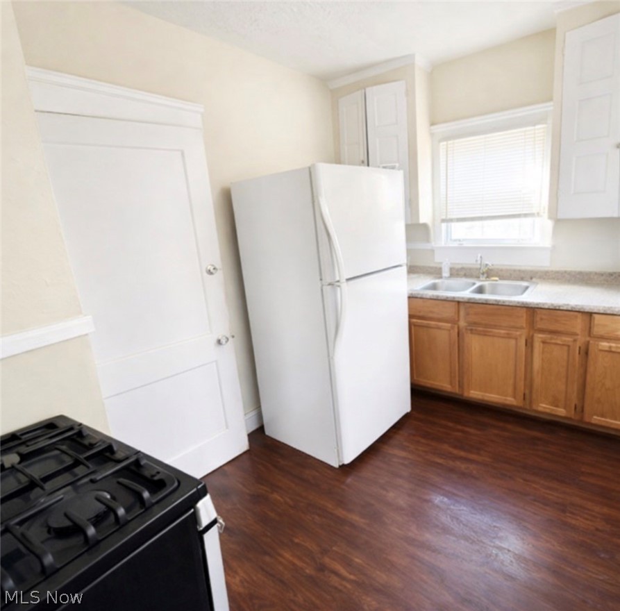 Kitchen with black range with gas cooktop, freestanding refrigerator, dark wood-type flooring, light countertops, and a textured ceiling