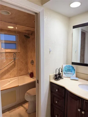 a bathroom with a bathtub shower sink vanity and toilet
