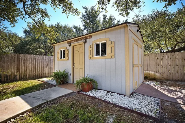 a backyard of a house with plants and trees with wooden fence