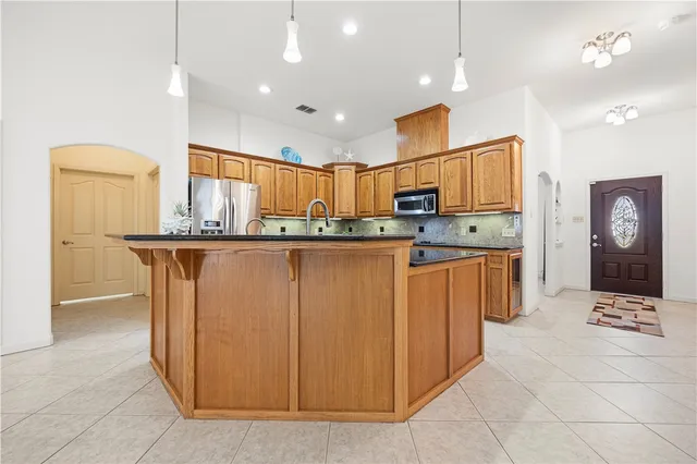 a kitchen with stainless steel appliances granite countertop a stove a sink a refrigerator and a microwave