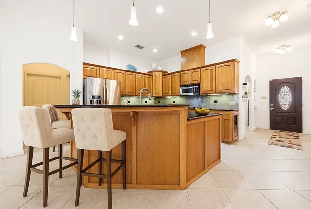 a kitchen with stainless steel appliances kitchen island granite countertop a table and chairs in it