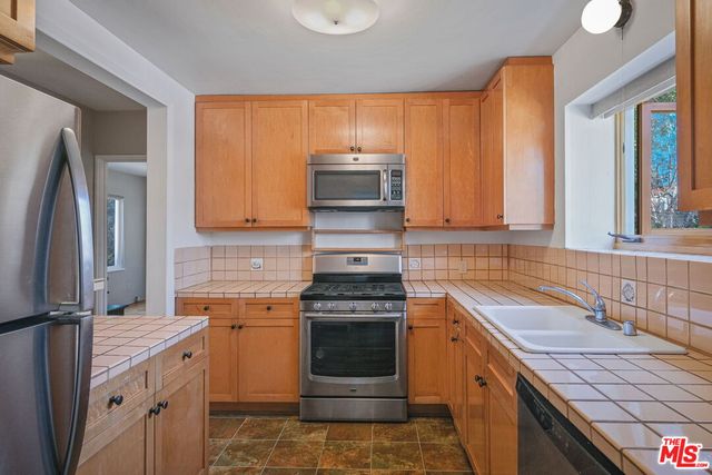 a kitchen with granite countertop a stove top oven microwave and refrigerator