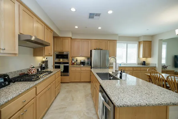a kitchen with kitchen island granite countertop a refrigerator a sink and a stove