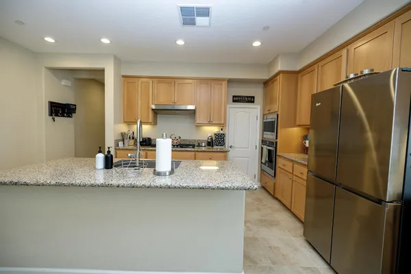 a kitchen with stainless steel appliances kitchen island granite countertop a refrigerator a stove a sink a dining table and chairs with wooden floor