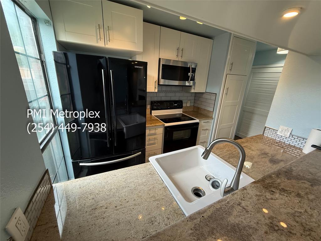 18240 Midway Road, Unit 606 Dallas, TX 75287 - Photo 12 of 25 a kitchen with stainless steel appliances granite countertop a refrigerator a stove and a sink with wooden floor