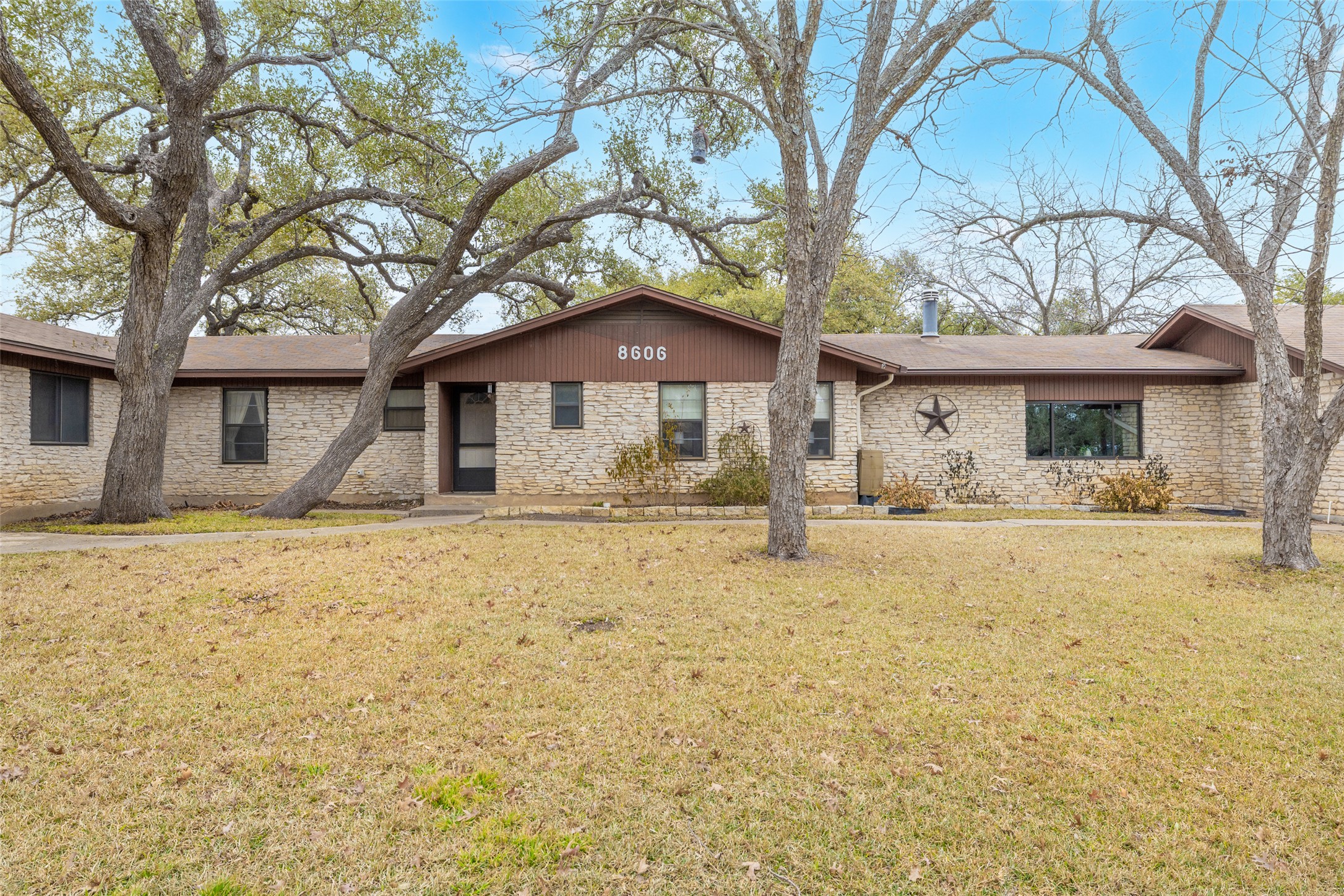 Ranch-style home with a front yard and stone siding