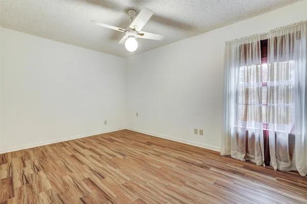 an empty room with wooden floor and fan