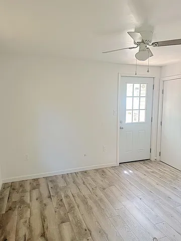 an empty room with wooden floor fan and windows