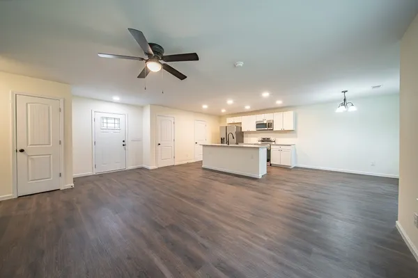 a view of a livingroom with a ceiling fan wooden floor and a ceiling fan