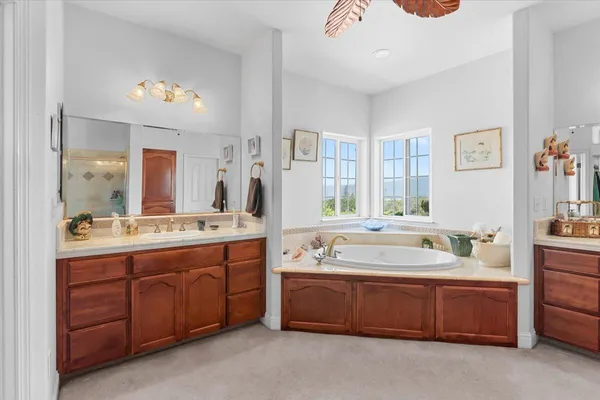 a spacious bathroom with a double vanity sink a large mirror and a bathtub
