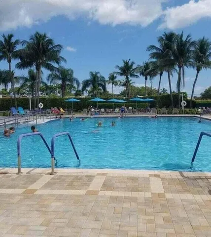 a view of swimming pool with a lawn chairs and palm trees