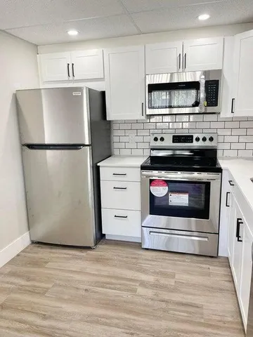 a kitchen with stainless steel appliances white cabinets and a refrigerator
