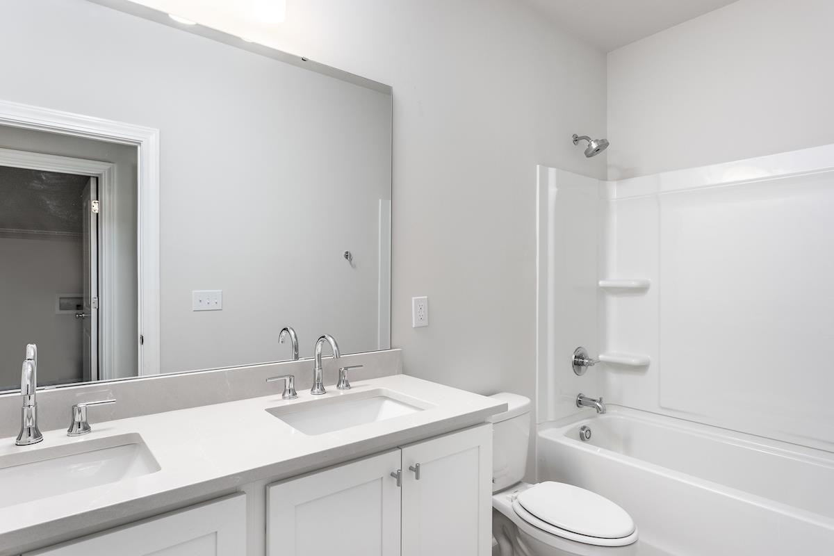 7804 Sofiana Avenue Raleigh, NC 27617 - Photo 20 of 28 a bathroom with a granite countertop sink a toilet and shower