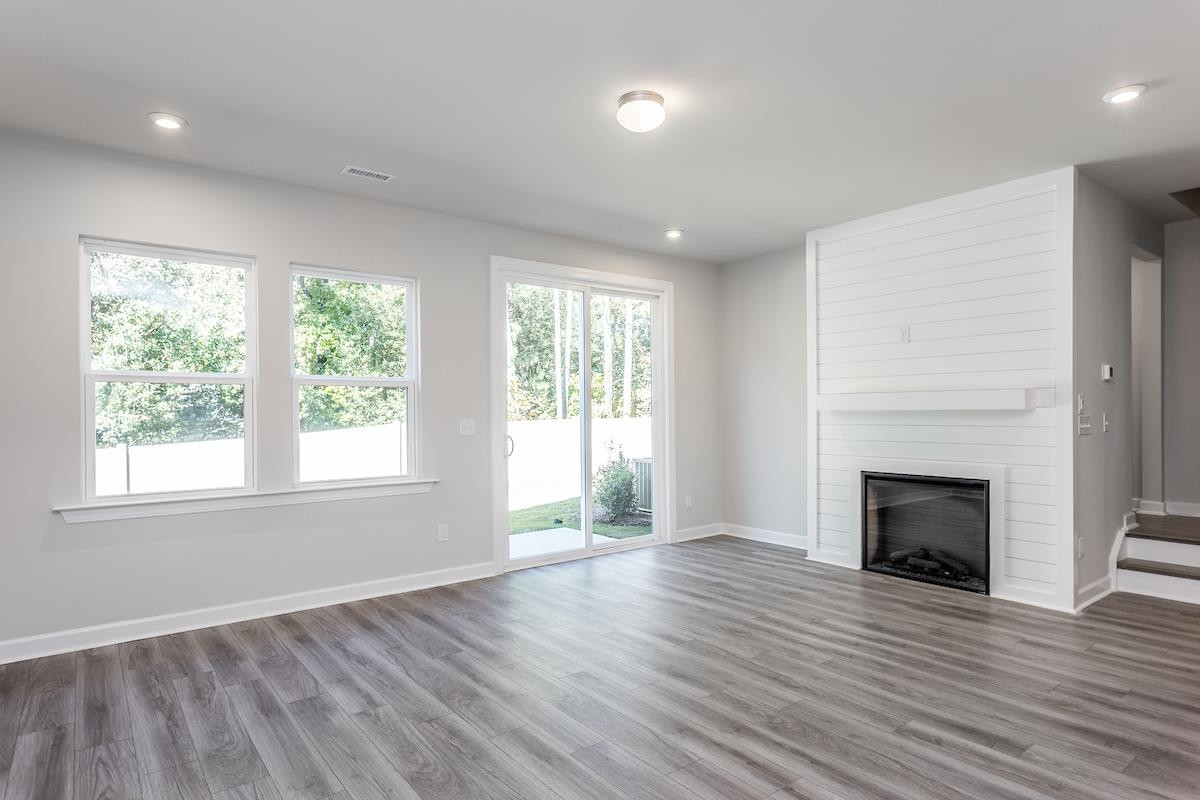 7804 Sofiana Avenue Raleigh, NC 27617 - Photo 8 of 28 an empty room with wooden floor fireplace and windows
