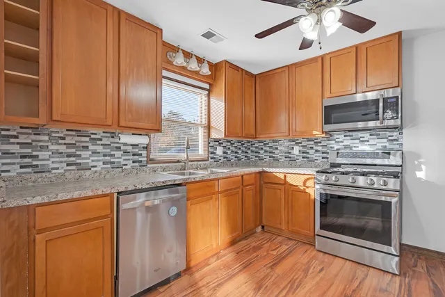 a kitchen with stainless steel appliances granite countertop wooden cabinets granite counter tops and a hard wood floors