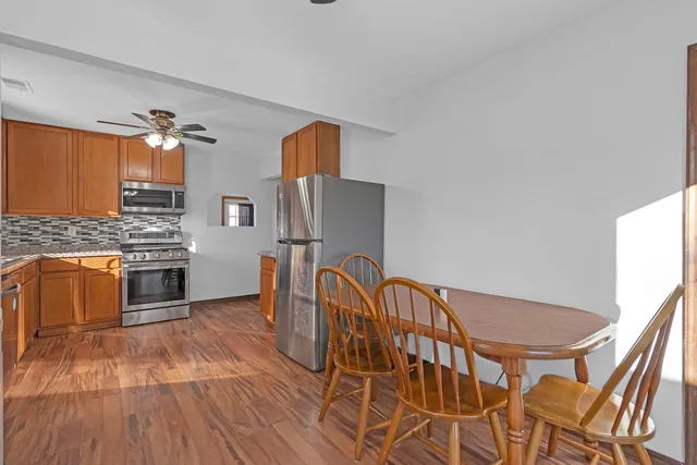 a kitchen with stainless steel appliances granite countertop a stove a sink dishwasher and a refrigerator with wooden floor