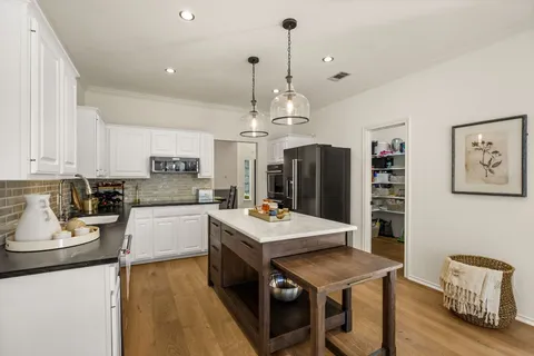 a kitchen with stainless steel appliances kitchen island granite countertop a stove a sink dishwasher and a refrigerator with wooden floor