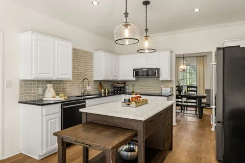 a kitchen with stainless steel appliances granite countertop a sink a stove and chairs